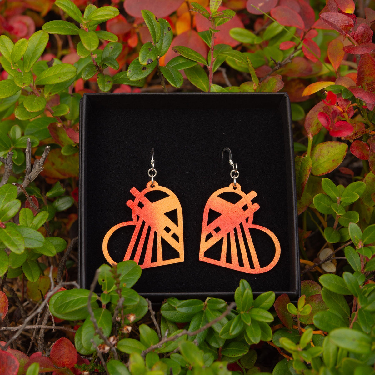Rovaniemi LOVE -malliston vaneriset oranssin sävyiset Rovaniemi-aiheiset korvakorut. Korujen kehämuoto on sydämen mallinen ja korun muodot muistuttavat Jätkänkynttilä sillasta.